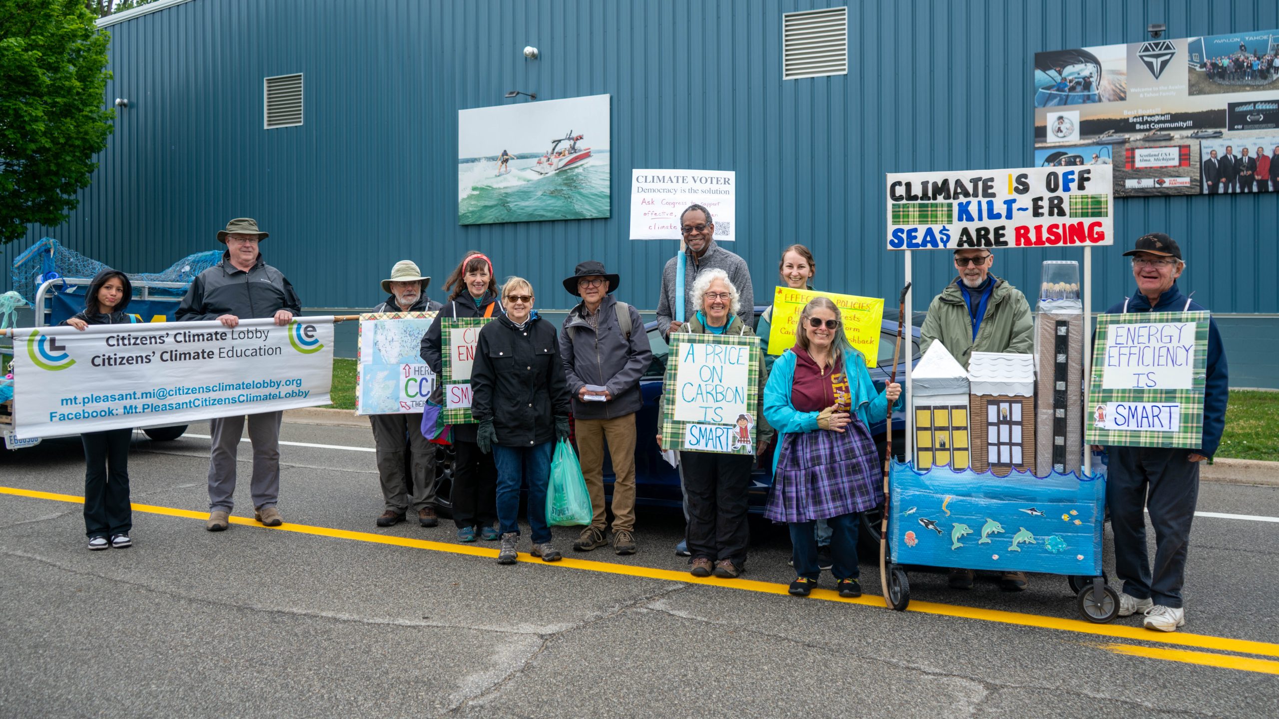 Group of protestors holding a sign at Mt Pleasant Citizens Climate Lobby at Alma Highland Festival 2026 5